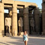 A client standing amidst the towering papyrus-bundle columns of Luxor Temple, conveying the immense scale and architectural beauty of the ancient Egyptian monument